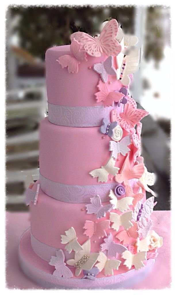 Butterfly garden cake featuring pink rosettes, green leaves, and flying butterflies